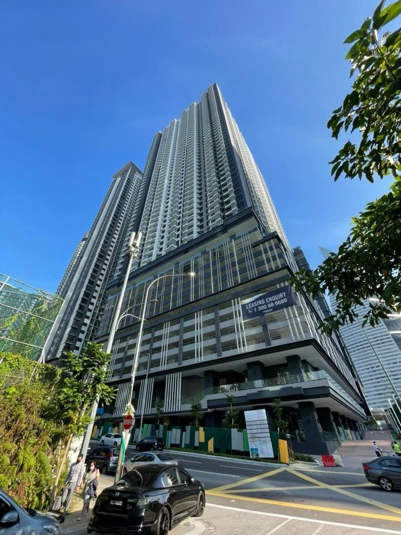 Exterior type: high-rise condominium; features: glass curtain wall, white painted facade, recessed balconies, multiple storeys, commercial space at ground level, surrounded by greenery, urban context with nearby roads; style: modern.